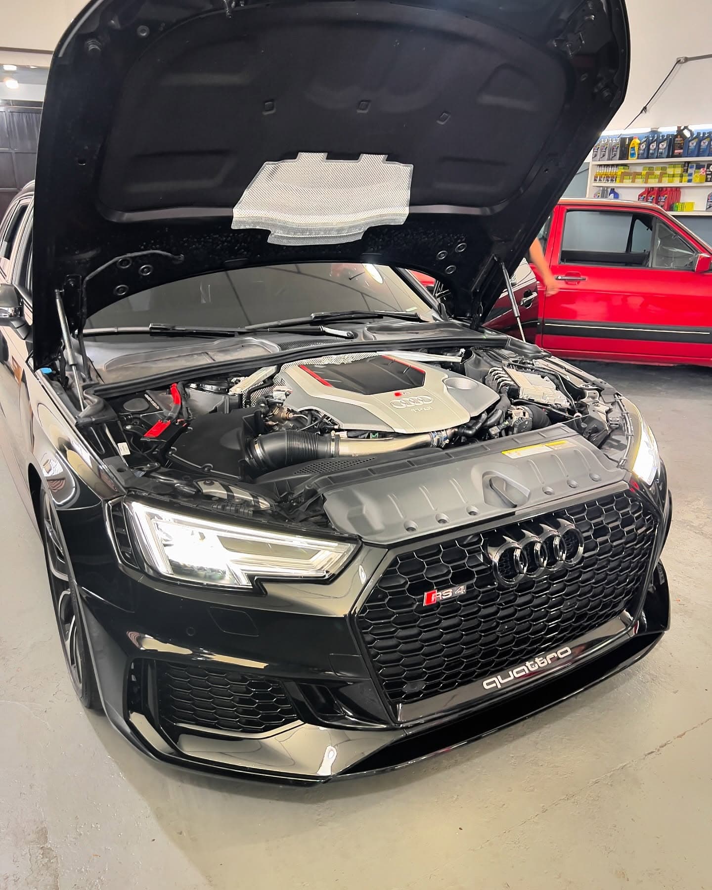 Audi RS4 preto de capô aberto, com a tampa vermelha do motor V6